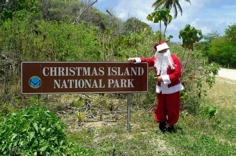 Santa standing beside the Christmas Island National Park sign.